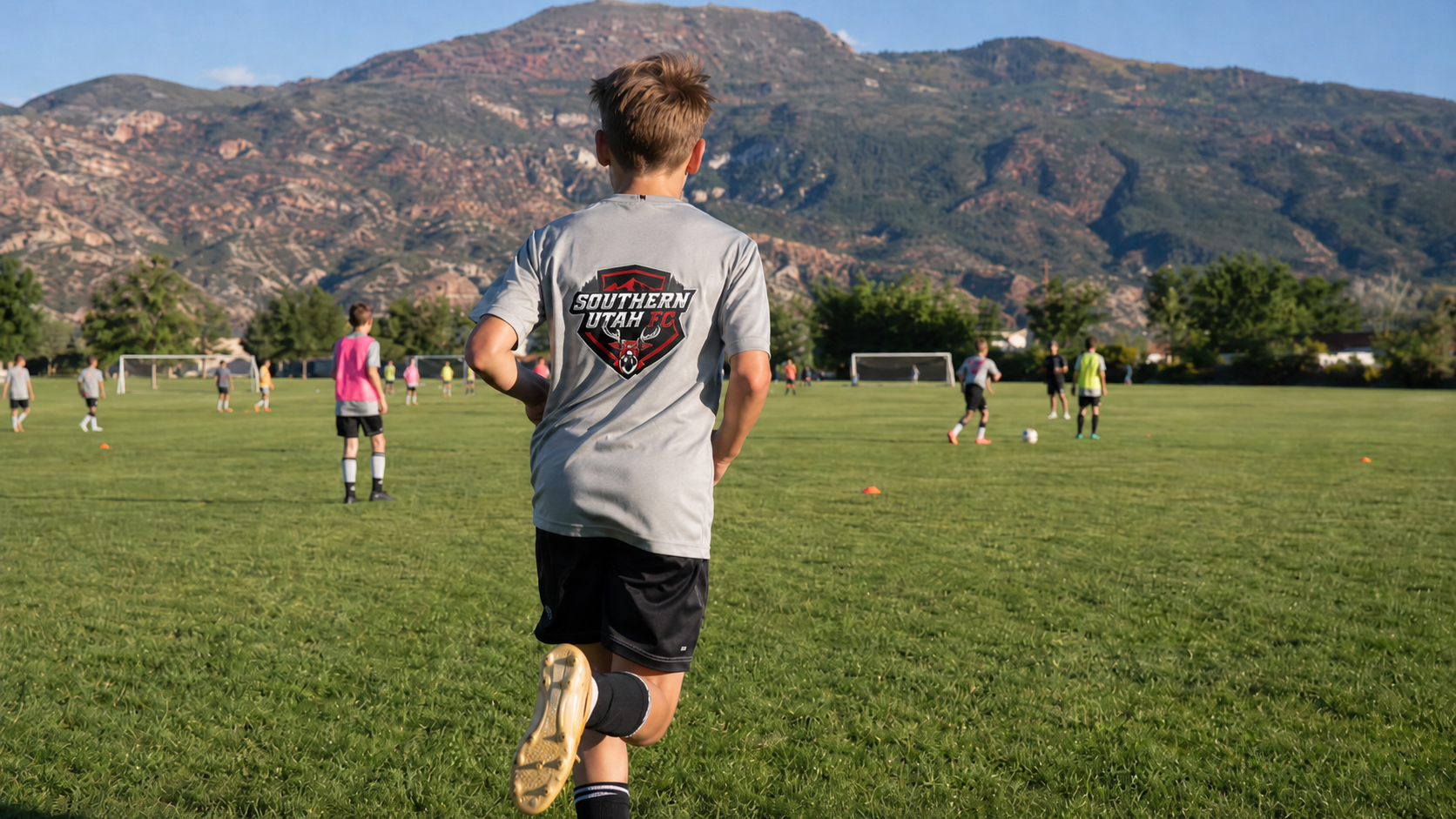 Young player running on a Southern Utah FC training field with mountains behind